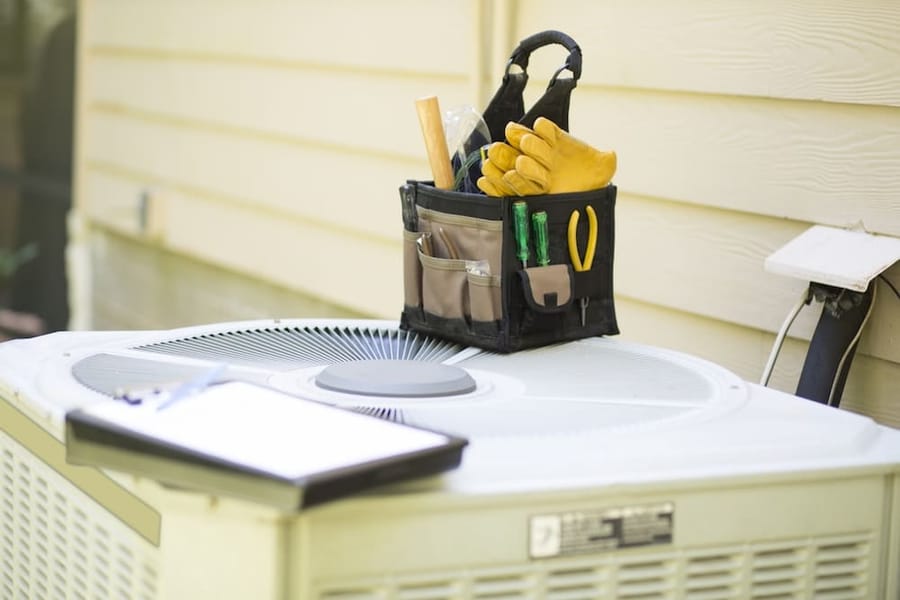 close up of HVAC unit with tool kit and gloves on top
